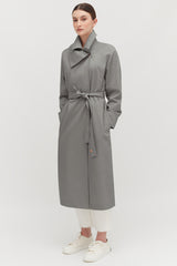 Person wearing a long belted coat, white pants, and sneakers.