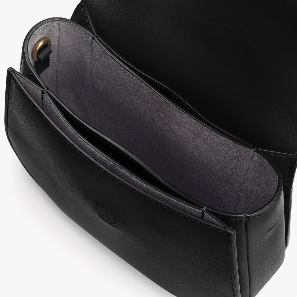 Open black handbag with visible compartments and a logo imprint inside.