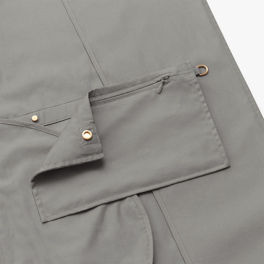 Cape with a zippered pocket and button closure detail.