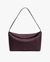 Handbag with curved top and single strap on white background