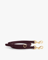Adjustable shoulder strap with gold clasps placed on a plain background.