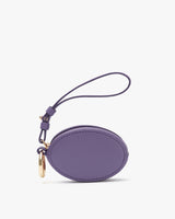 Small circular purse with wrist strap and metal clasp.