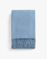 Blanket with fringes folded on a plain background.