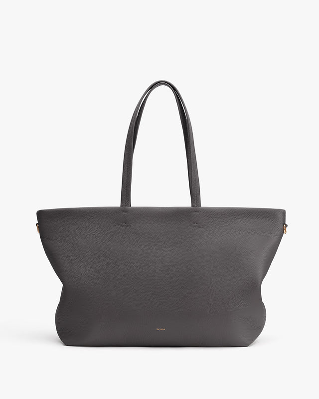 Large handbag with long handles on a flat surface.