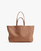 Large leather tote bag standing upright with handles.