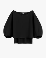 Black blouse with voluminous sleeves and layered hem.
