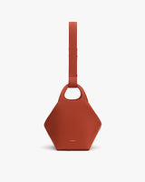 Hexagonal handbag with wide strap and round cut-out handle.