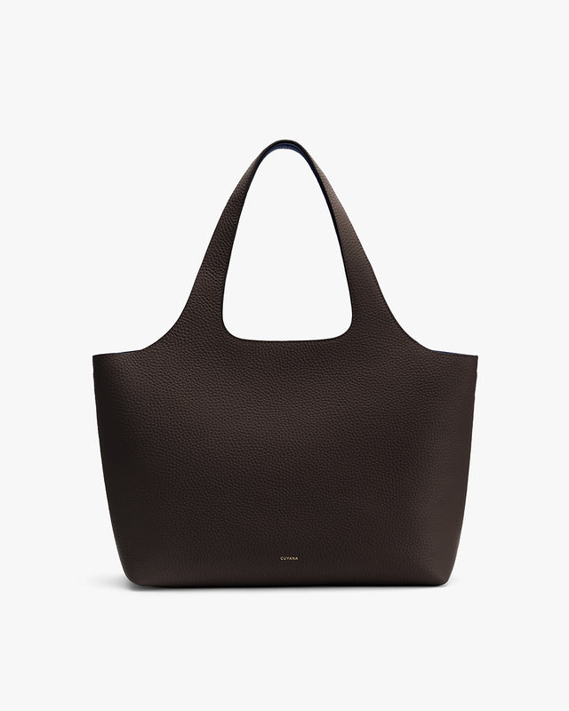 Handbag with two handles and pebbled leather surface on plain background