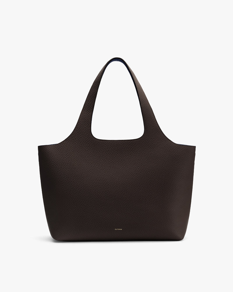 Handbag with two handles and pebbled leather surface on plain background