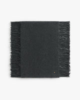 Rectangular scarf with fringed edges laid flat.