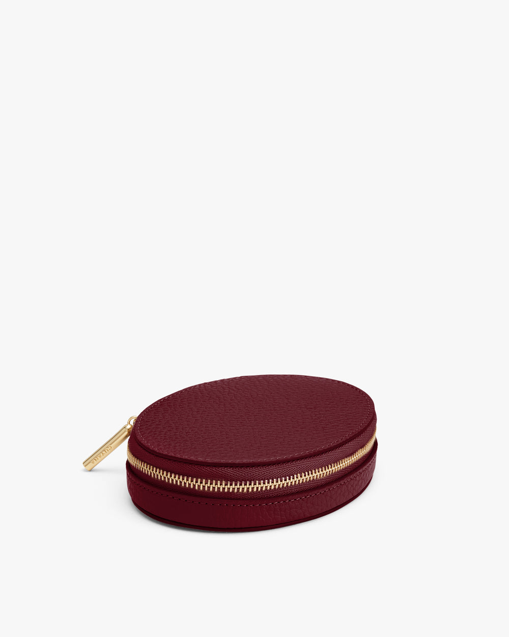 Round leather zippered case with gold-toned zipper on white background.