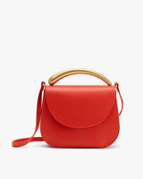 A handbag with a curved handle on top.