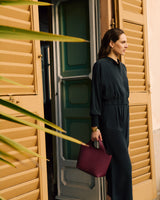 Person standing in doorway holding a handbag