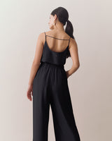 Woman wearing sleeveless top and wide-leg pants, with hand in pocket