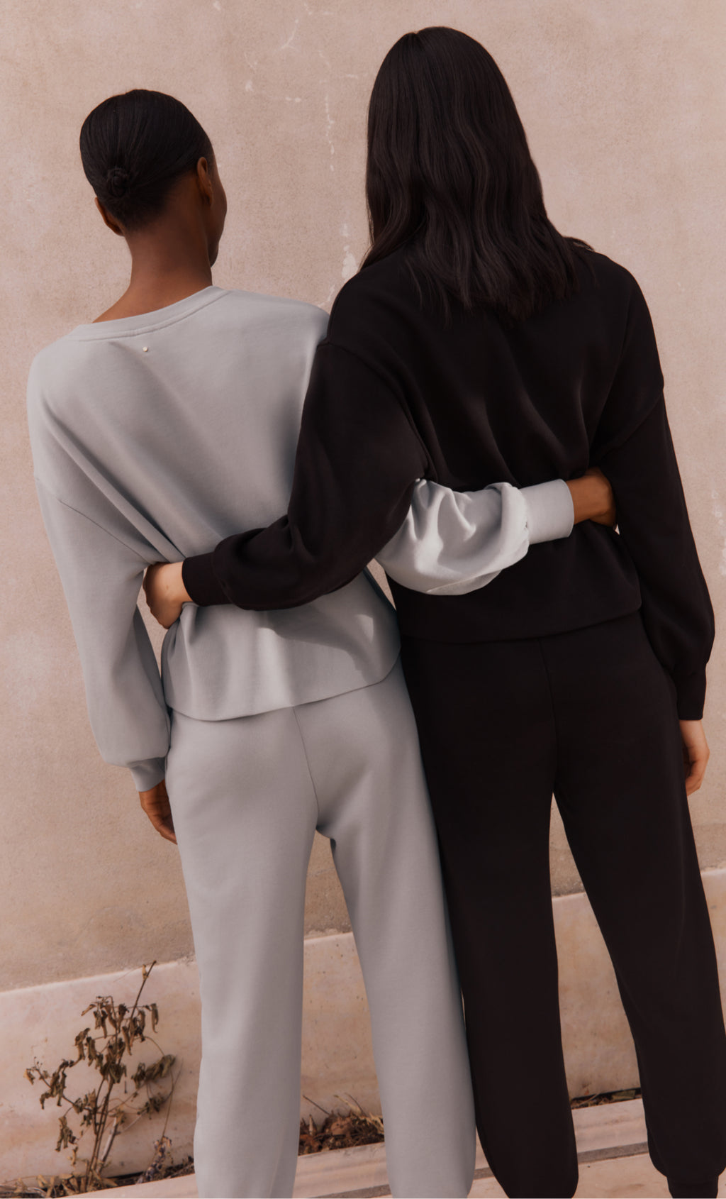 Two people in casual outfits with arms around each other.