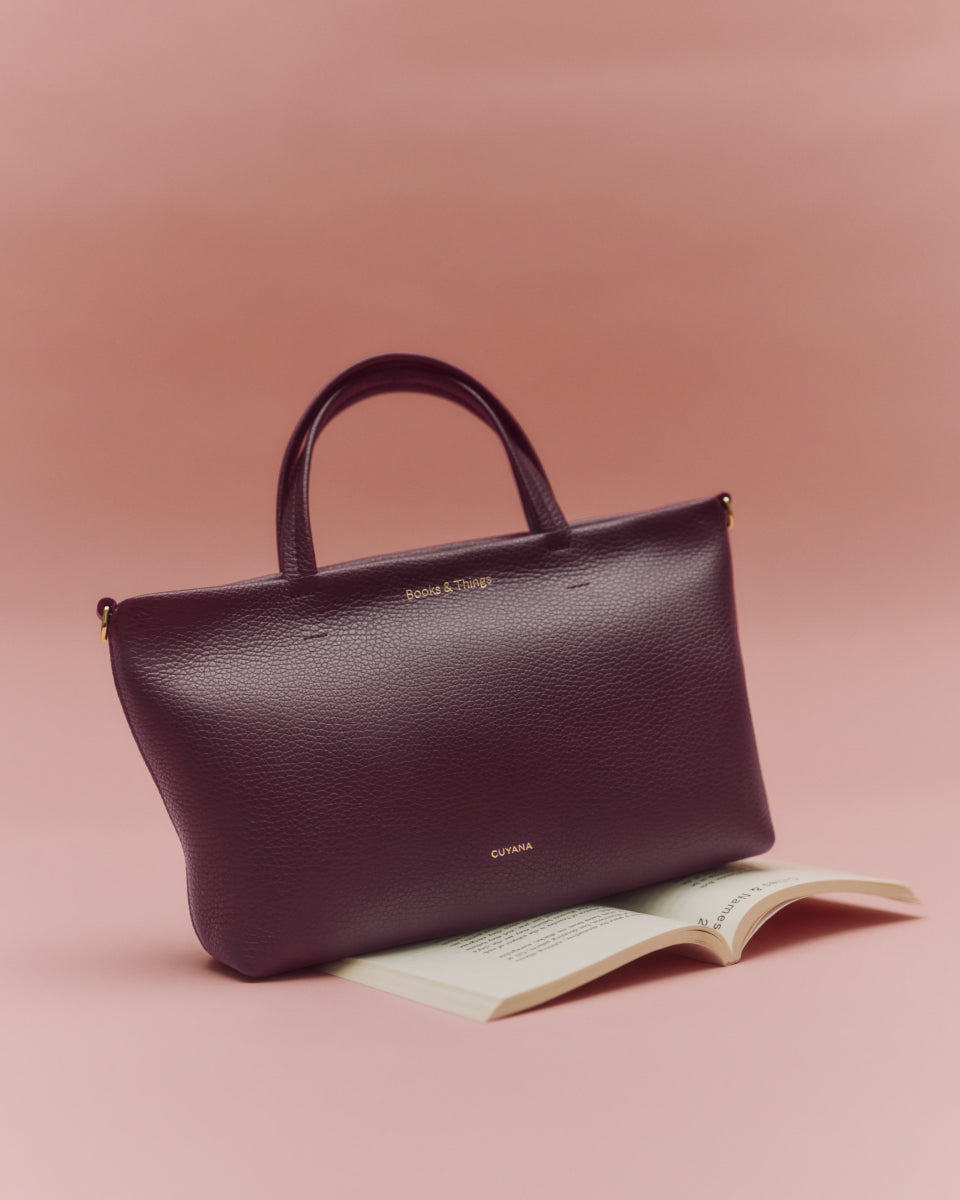 Tote bag resting on an open book with a plain background.