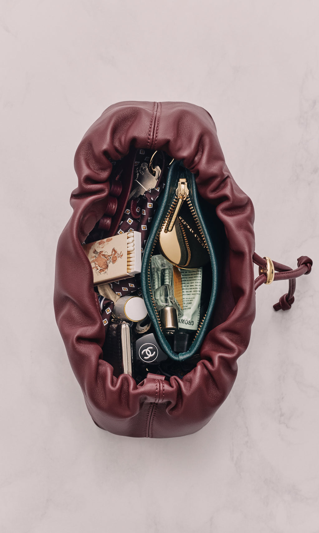 Open drawstring bag containing makeup and personal items.