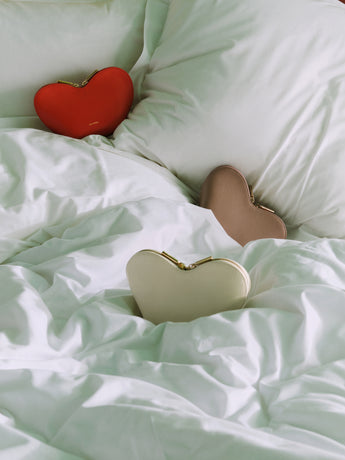 Heart-shaped bags on a bed with pillows.