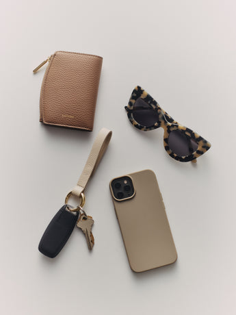 Wallet, sunglasses, phone with case, and car key on a surface.