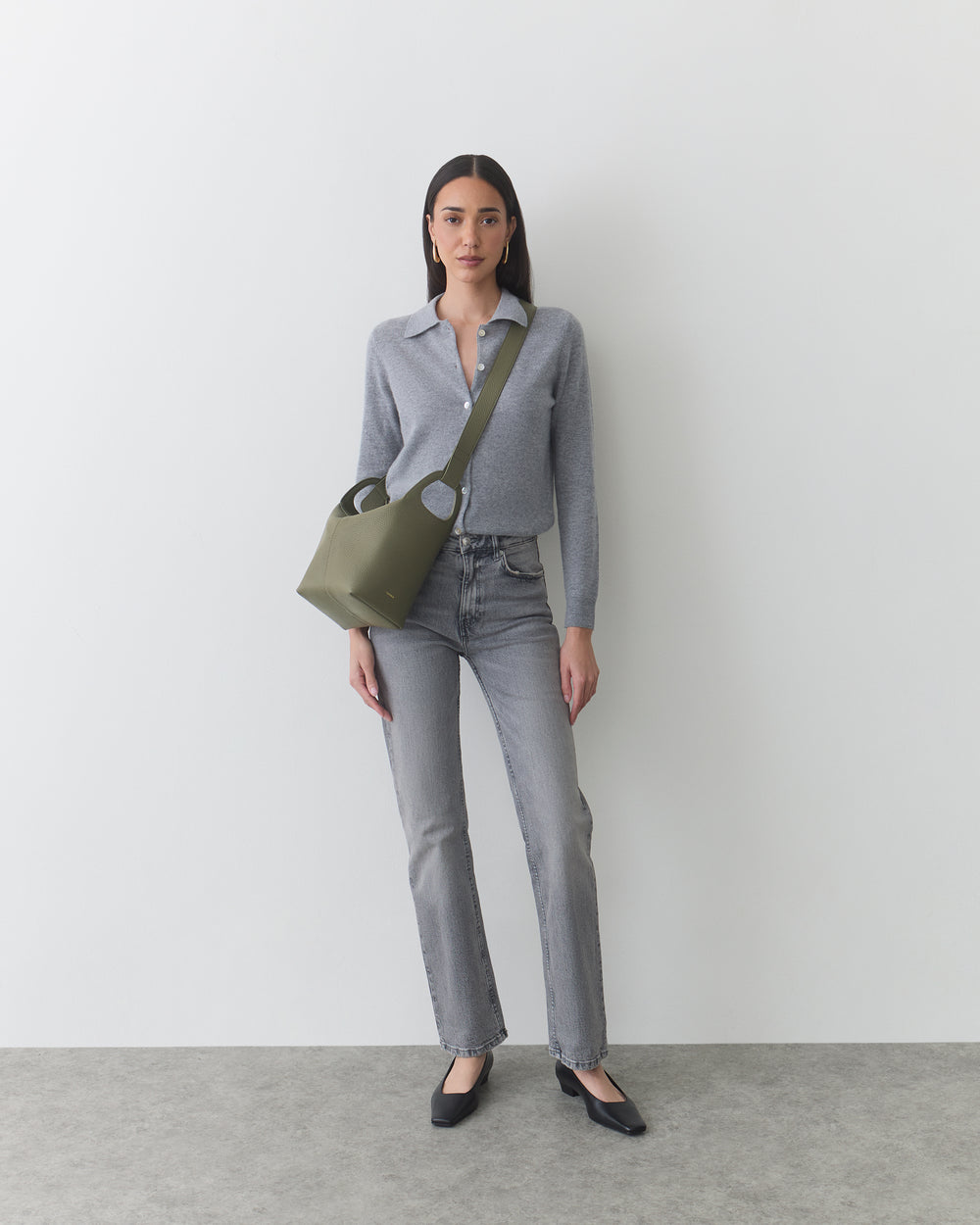 Person wearing jeans and a long-sleeve shirt, carrying a shoulder bag.