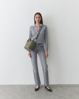 Person wearing jeans and a long-sleeve shirt, carrying a shoulder bag.
