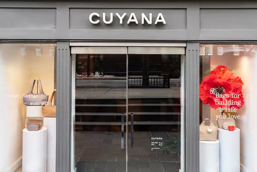 Storefront with glass doors and display items on pillars on both sides.