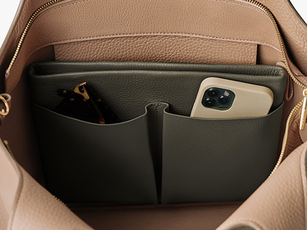 Inside a bag with two pockets holding glasses case and smartphone.