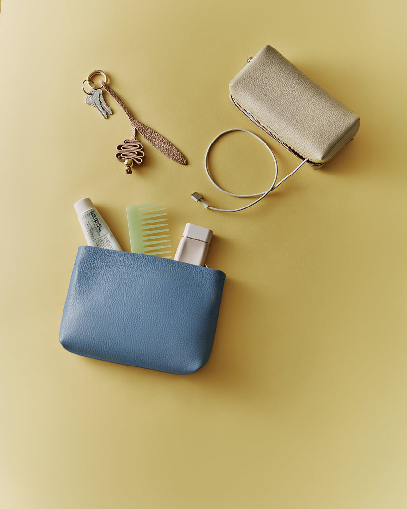 Two pouches, keys, comb, cables, and toiletries on a flat surface.