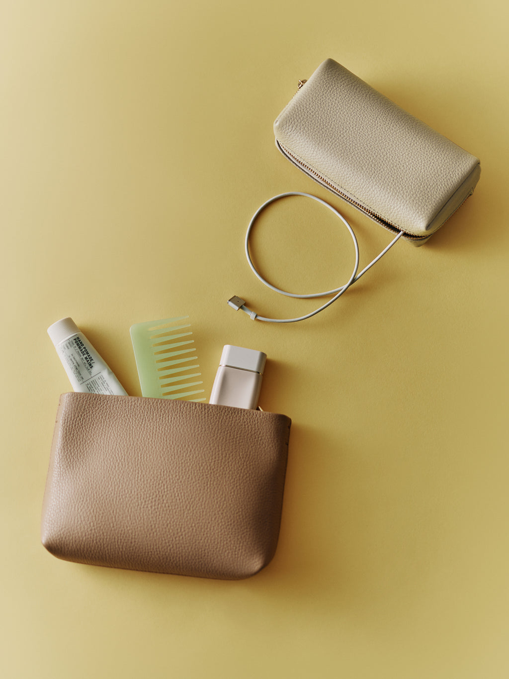 Two cosmetic bags, one containing a comb, lotion, and spray bottle.