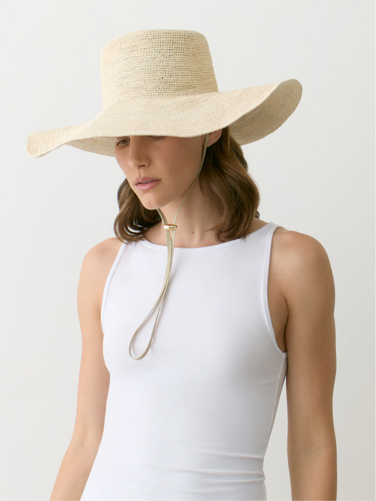 Person wearing a sun hat and sleeveless top with chin strap fastened.