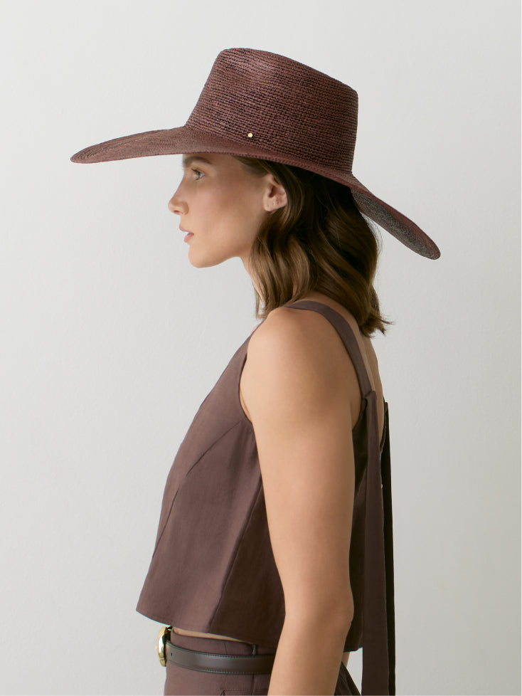 Person wearing a wide-brim hat and sleeveless top, profile view.