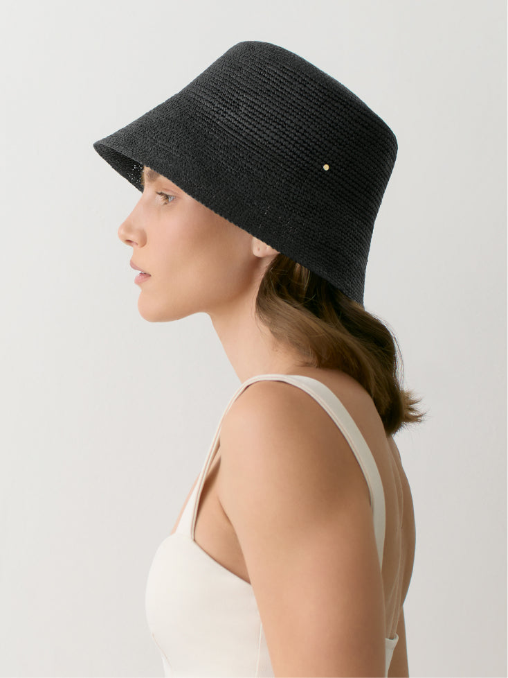 Person wearing a hat and tank top, shown in side profile view.