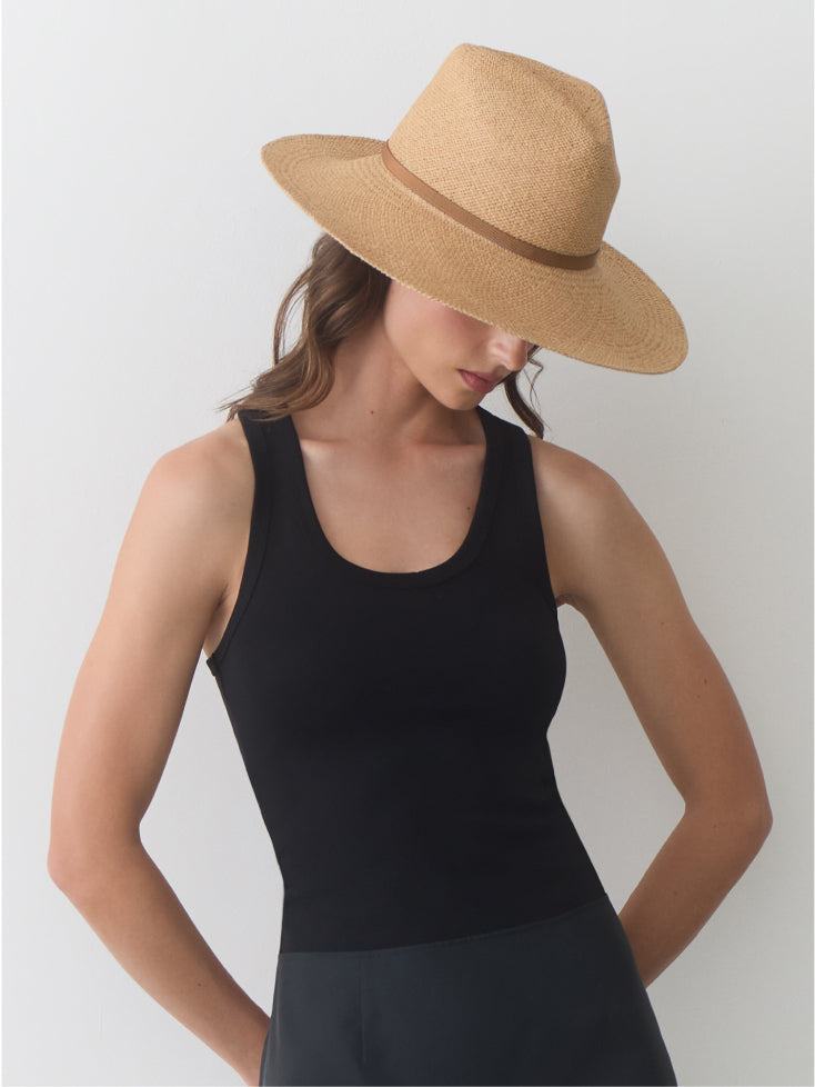 Person wearing a sleeveless top and a wide-brimmed hat.
