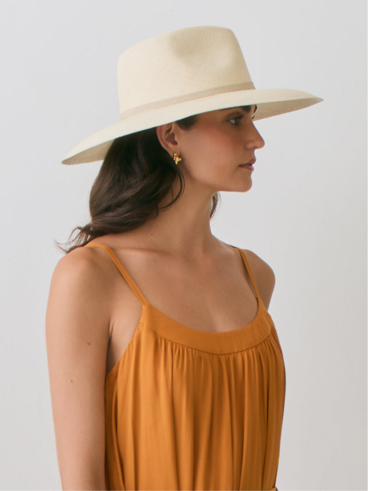 Woman wearing a wide-brimmed hat and sleeveless dress, shown in side profile.