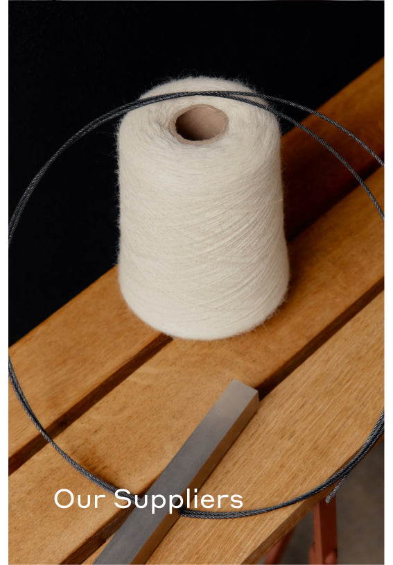 Spool of yarn with a measuring tool and wire on a wooden surface.