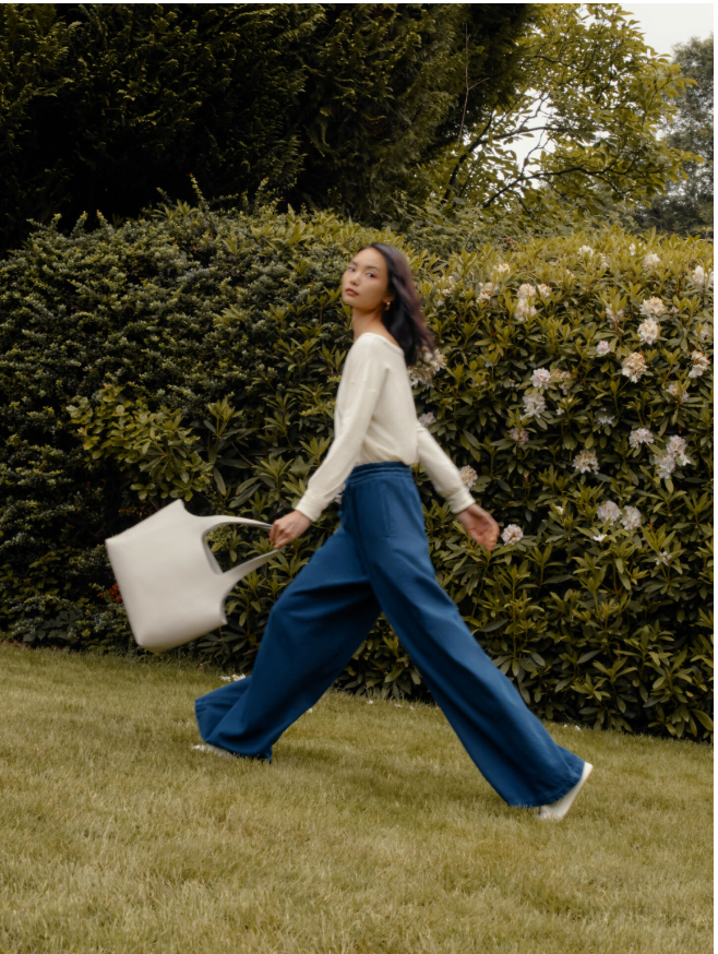 Woman walking in a garden with a watering can.