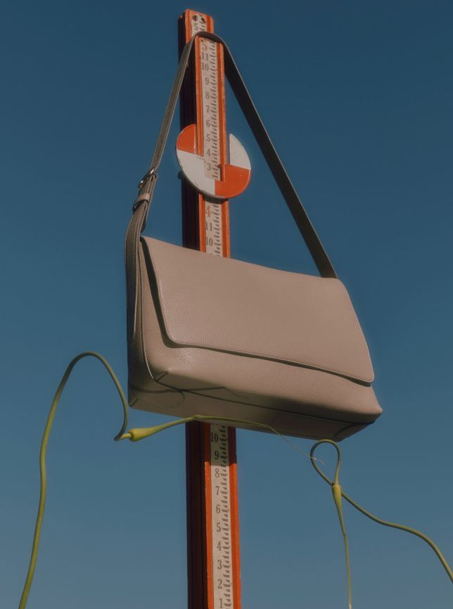 Purse hanging on a measuring stick with vines wrapped around.