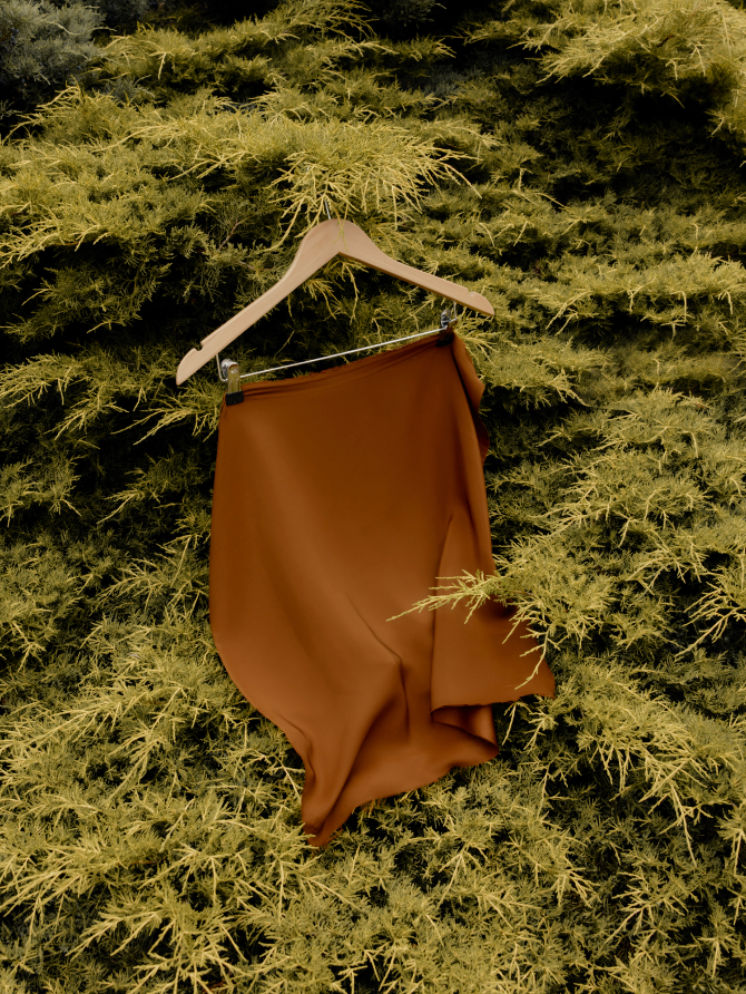 A skirt on a hanger suspended among dense foliage.