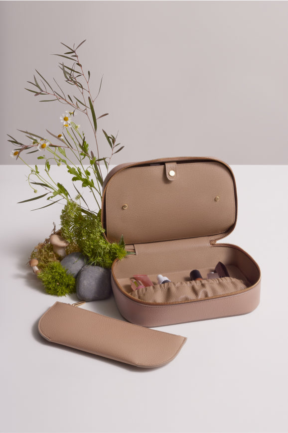 Open jewelry box with contents displayed, accompanied by an arrangement of plants and a detached cover nearby.