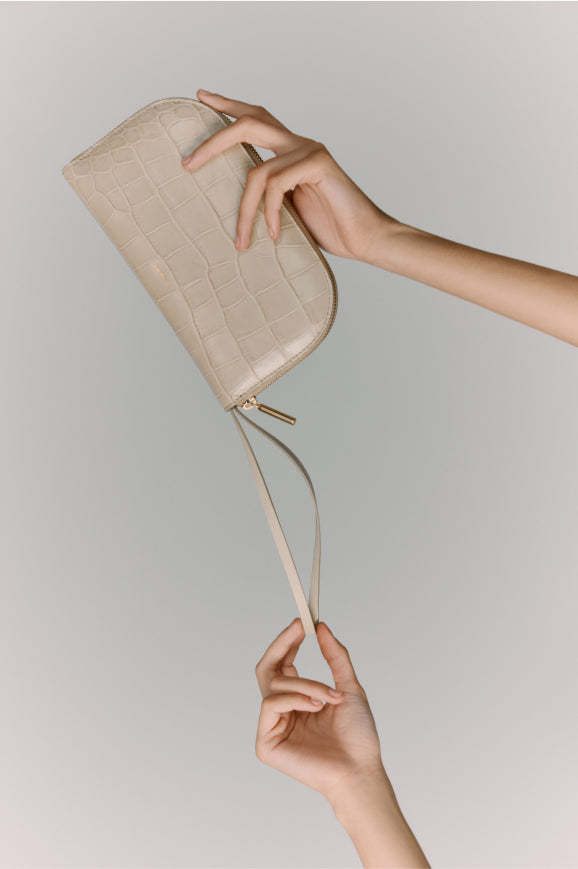 Hand holding a wristlet bag against a light background