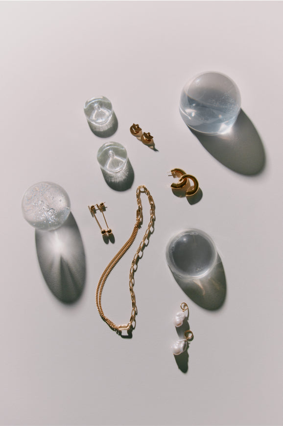 An arrangement of various shaped glass objects and pieces of jewelry on a surface.