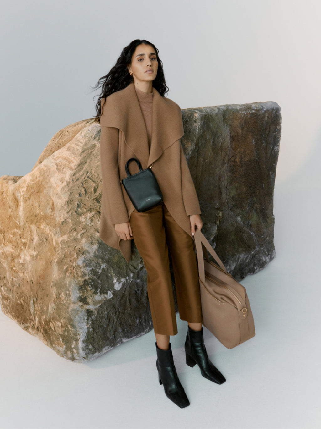 Woman standing next to large rock with bags