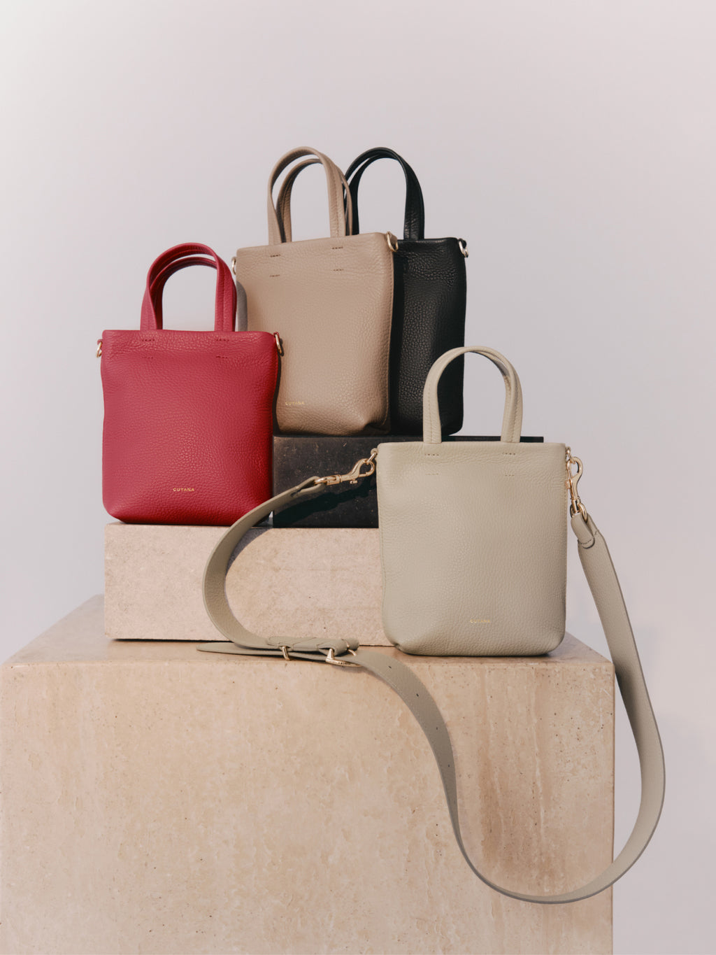 Four handbags displayed on a podium.