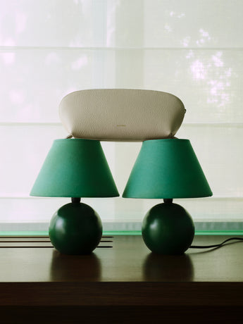 Two lamps on a table with a clutch bag resting on top.