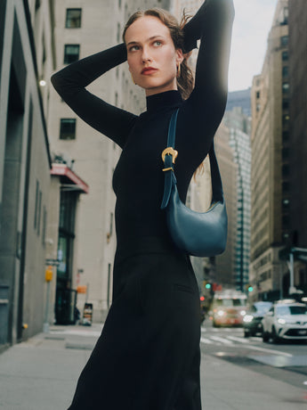 Person standing on city street with small shoulder bag