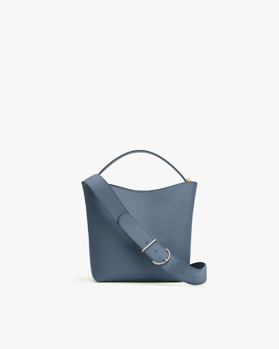 Handbag with a handle and shoulder strap on plain background.