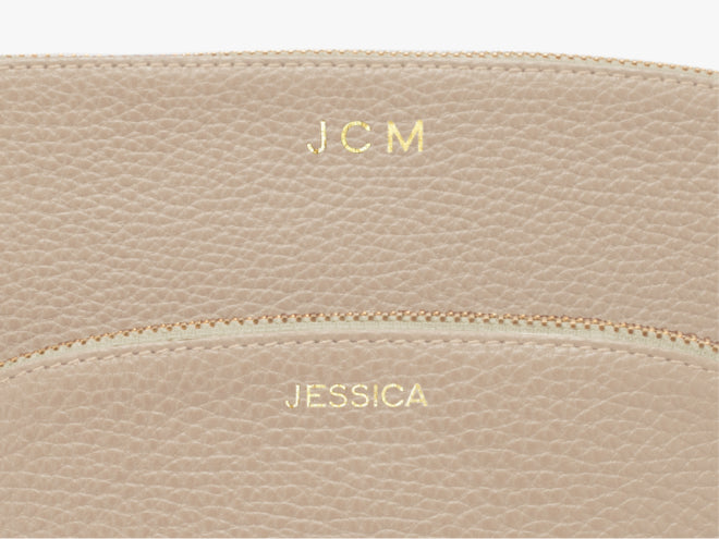 Close-up of a textured leather item with initials and name embossed.
