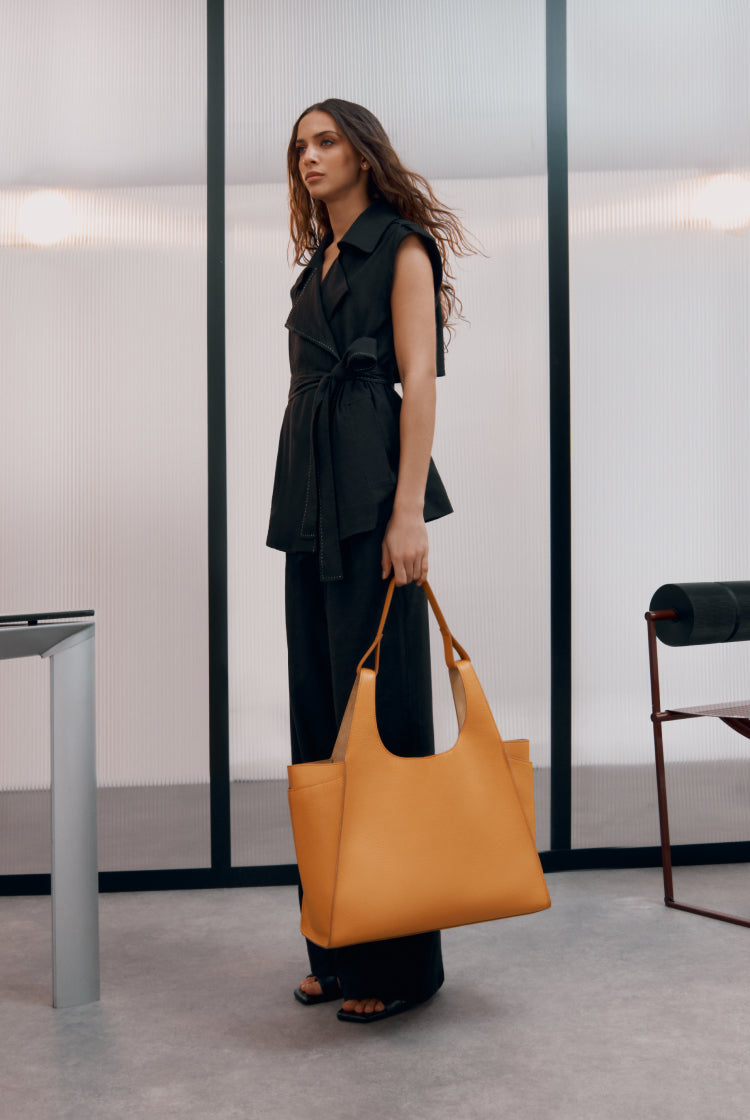 Woman standing in a room holding a large bag.