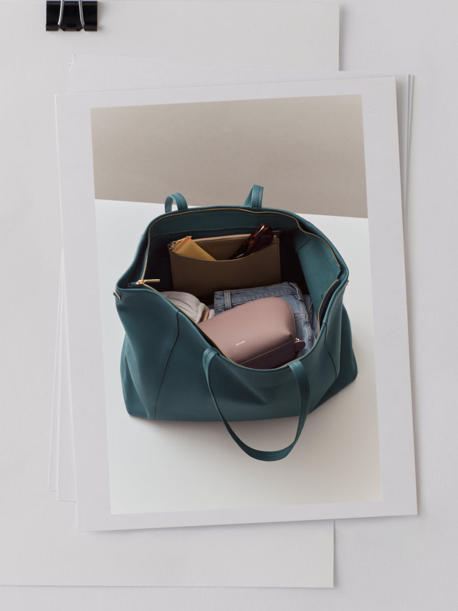 A handbag with items like pouches, clothing, and a pair of sunglasses inside.