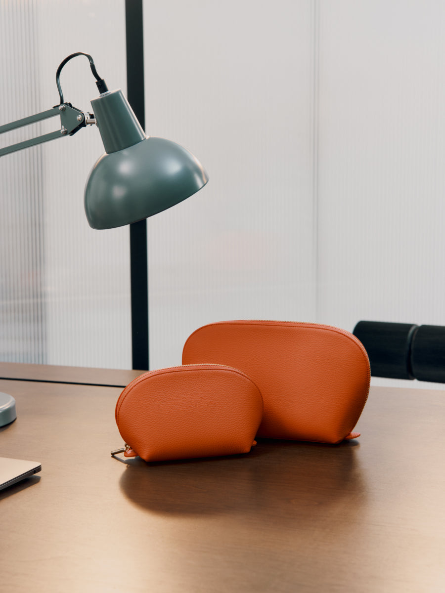 Desk with two pouches, a lamp, and part of a laptop.